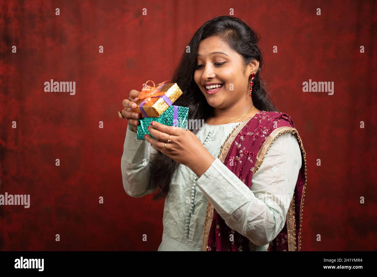 Ritratto girato di donna indiana eccitata da apertura scatola regalo sorpresa - concetto showinf di compleanno, anniversario di valentine o regali inaspettati Foto Stock