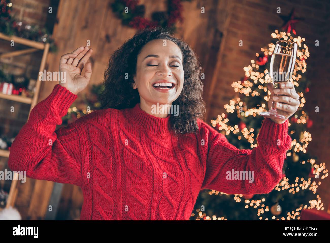 Foto di ispirazione funky sognante signora tenere vetro vino vicino occhi danza indossare pullover in casa decorata interni Foto Stock