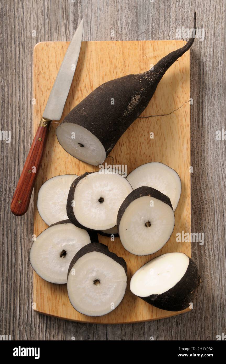 Rafano nero, parzialmente affettato, su un tagliere Foto Stock