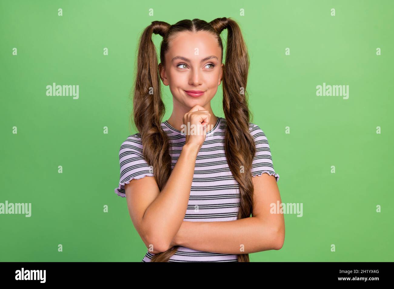 Ritratto di attraente allegro astuzia pensive ragazza dai capelli lunghi che prende la decisione isolato su sfondo verde di colore Foto Stock
