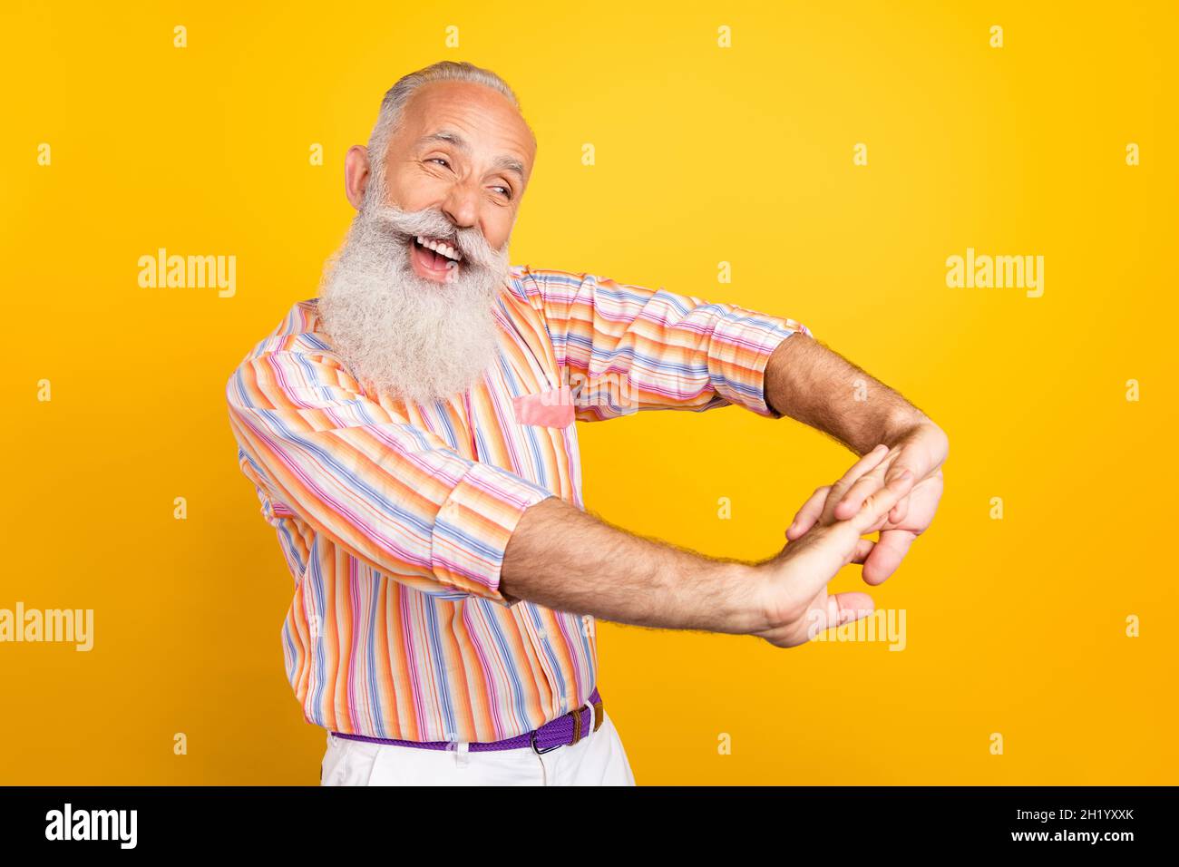 Ritratto di attraente uomo allegro grigio-capelli che ha divertimento limbering su mani isolate su sfondo di colore giallo vivo Foto Stock