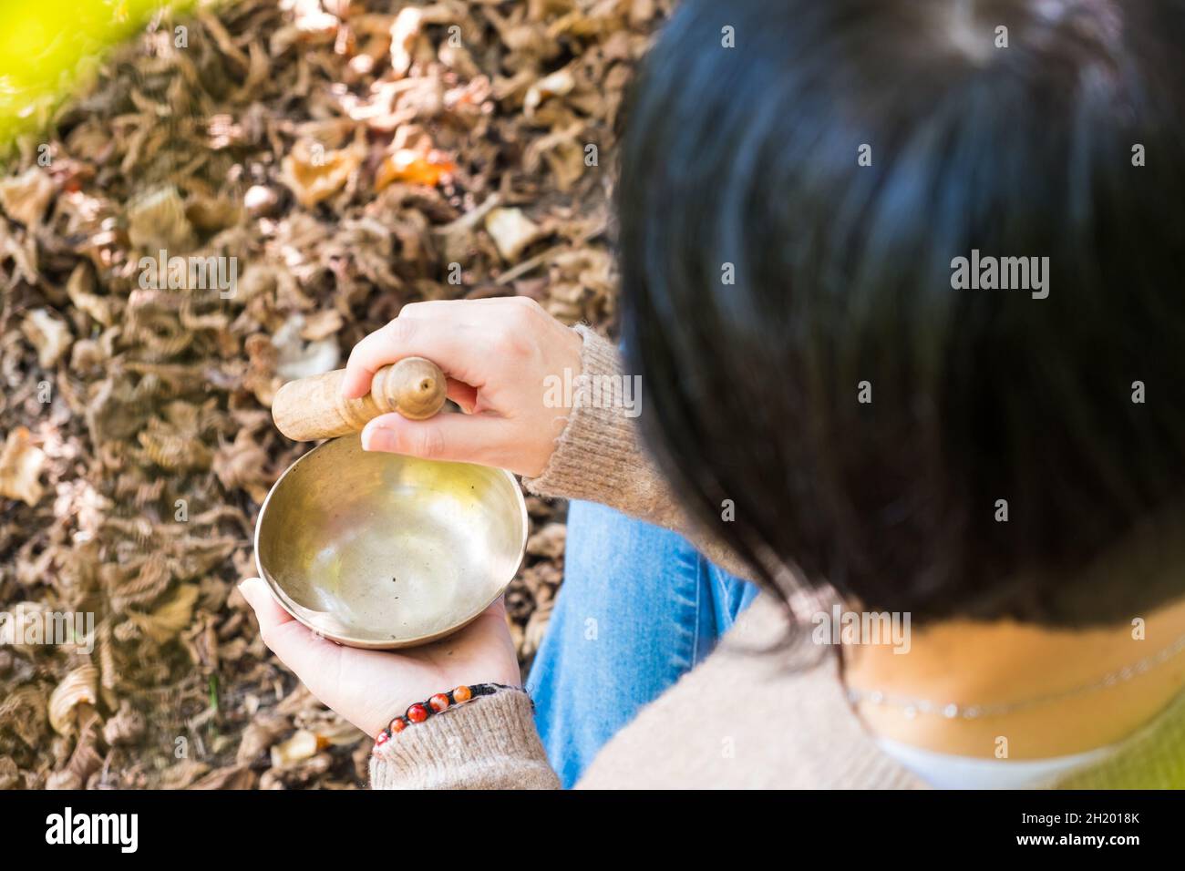 Donna che gioca su una ciotola di canto tibetano per la terapia sonora in atmosfera di guarigione, meditazione e relax. Foto Stock