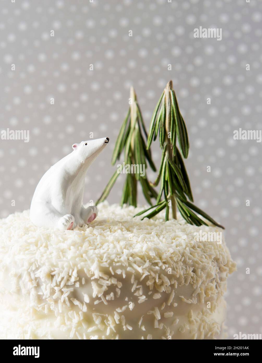 Torta di cocco decorata per Natale con rosmarino e un orso polare, in un ambiente nevoso Foto Stock