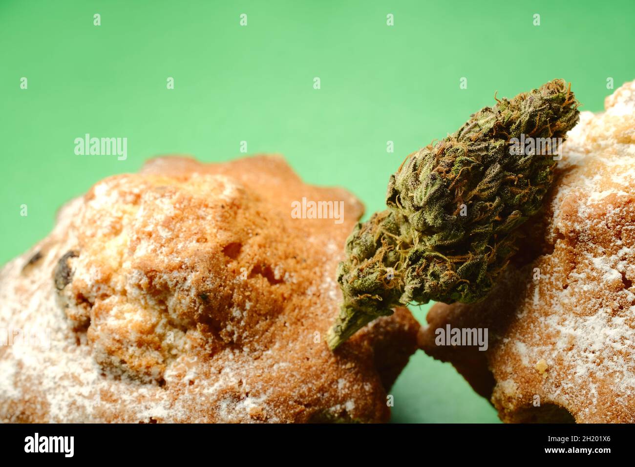 Cucinato con Cannabis. Dolce cupcake con germoglio marijuana, vista macro. Torte di erbacce con olio CBD e fioritura di cannabis isolato su sfondo verde. Marijuan Foto Stock