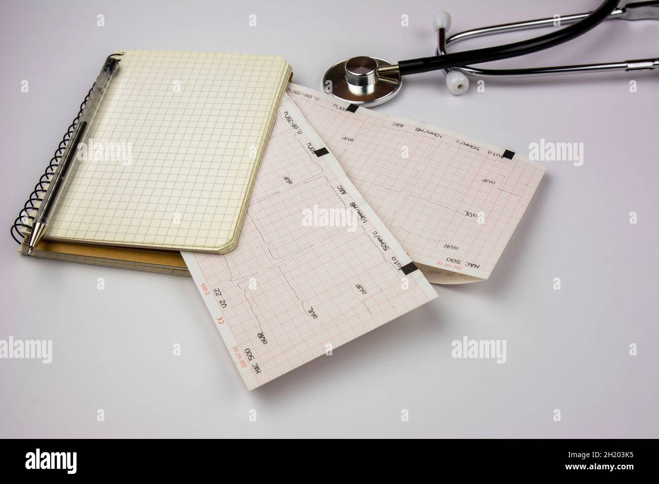 Fogli per stetoscopio, blocco note ed elettrocardiogramma. Scrivania del medico cardiologo. Medicina e concetto di salute Foto Stock