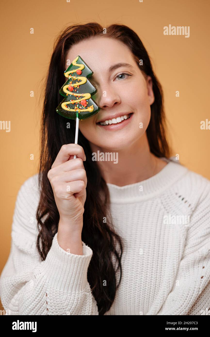 Donna sorridente che tiene dolce albero di Natale lecca lecca caramella. Foto Stock