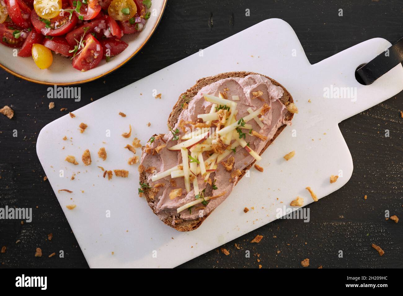 Una fetta di pane spalmata con pâté di fegato e mela, servita con insalata di pomodoro Foto Stock