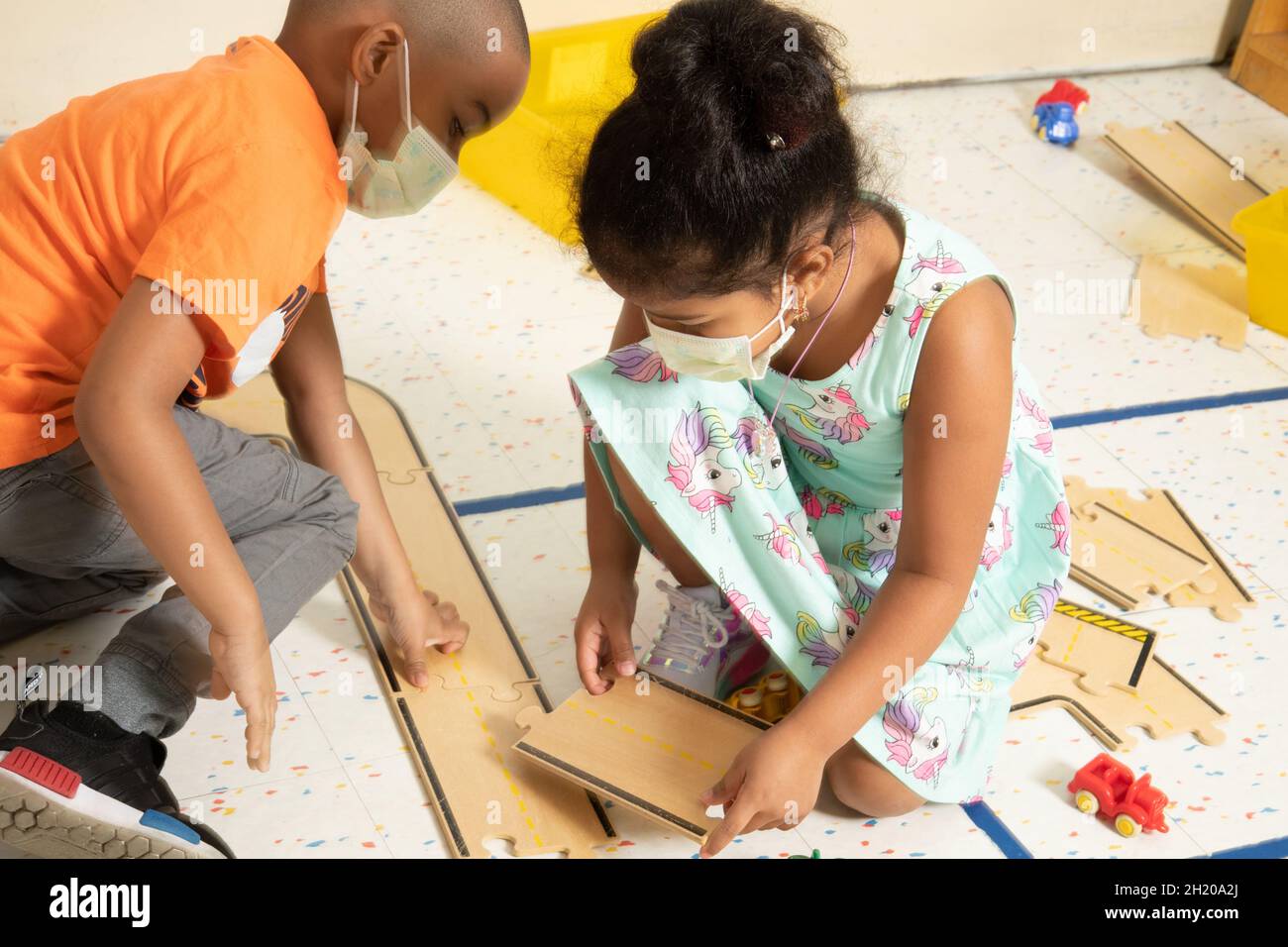 Istruzione Preschool 4-5 anni ragazzo e ragazza giocare insieme con pezzi di legno strada che si adattano insieme come pezzi puzzle puzzle giocare nel blocco A. Foto Stock