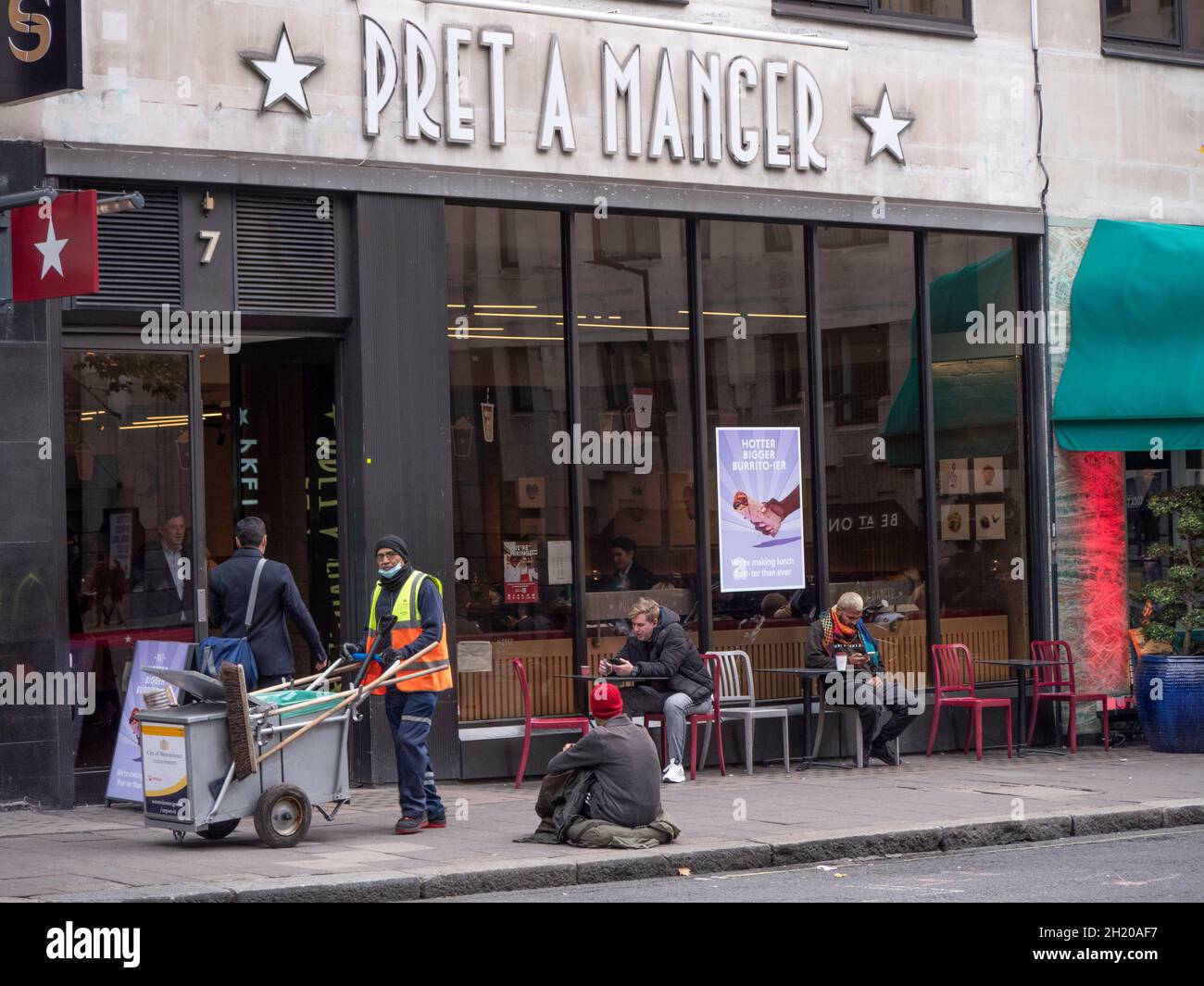 I ricchi poveri dividono la disuguaglianza, Pret un manger ristorante Mayfair, con spazzatrice stradale che passa e mendicante senzatetto seduto sul marciapiede che chiede Foto Stock