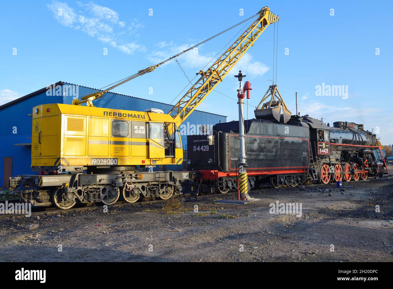 SORTAVALA, RUSSIA - 07 OTTOBRE 2021: La gru ferroviaria KZh-462 carica il carbone in una locomotiva a vapore sovietica per il trasporto merci serie L (L-4429, Lebedyanka) a Sortava Foto Stock