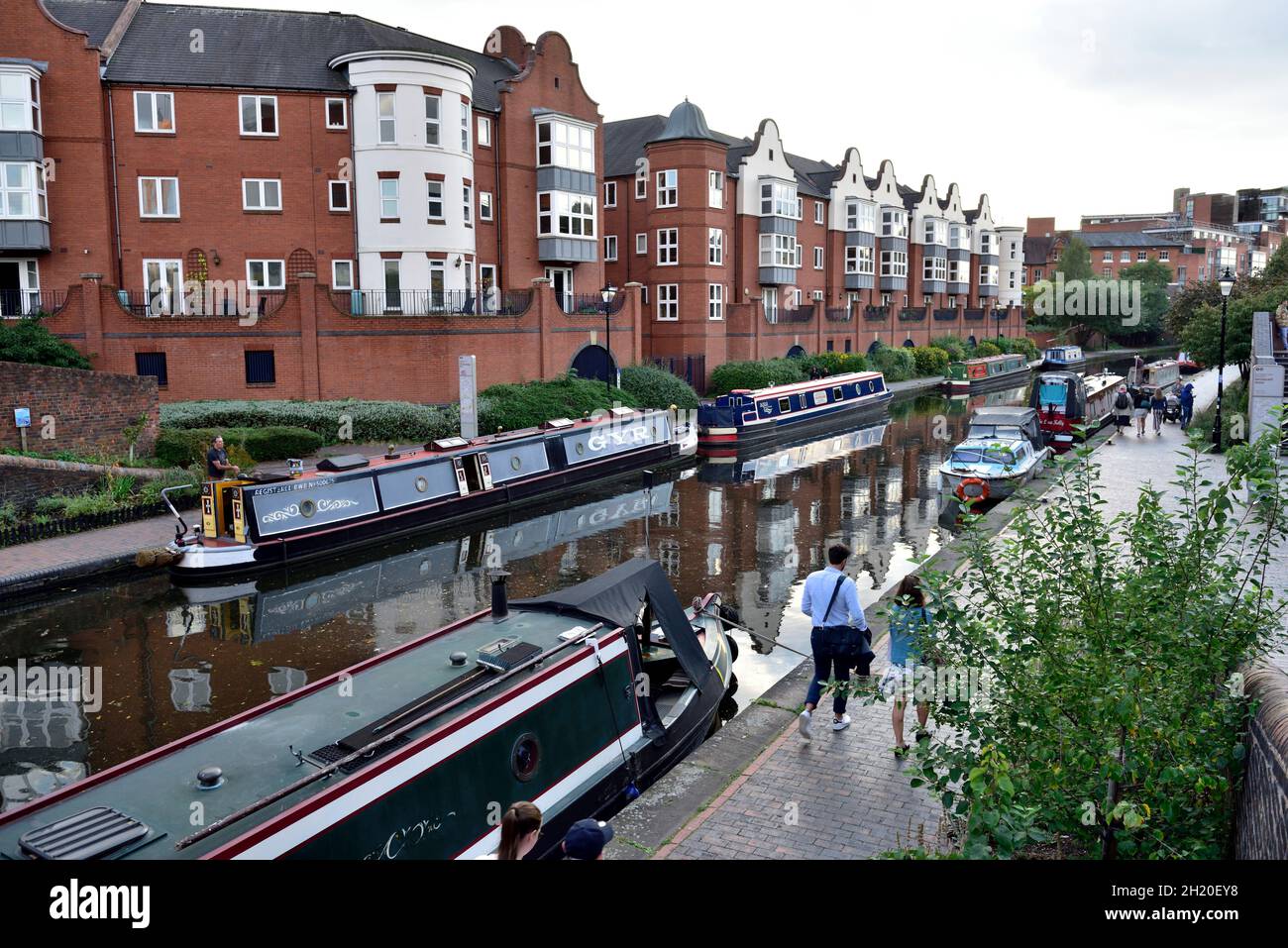 Le barche strette del canale ormeggiate sulla linea vecchia del canale di Birmingham con gli edifici di appartamenti moderni (corte sinfonica, Regno Unito Foto Stock