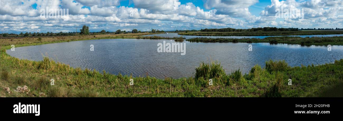 Vista panoramica su fenland e paludi e il fiume Ouse vicino a Ely in Cambridgeshire East Anglia Inghilterra con barca sul fiume Foto Stock