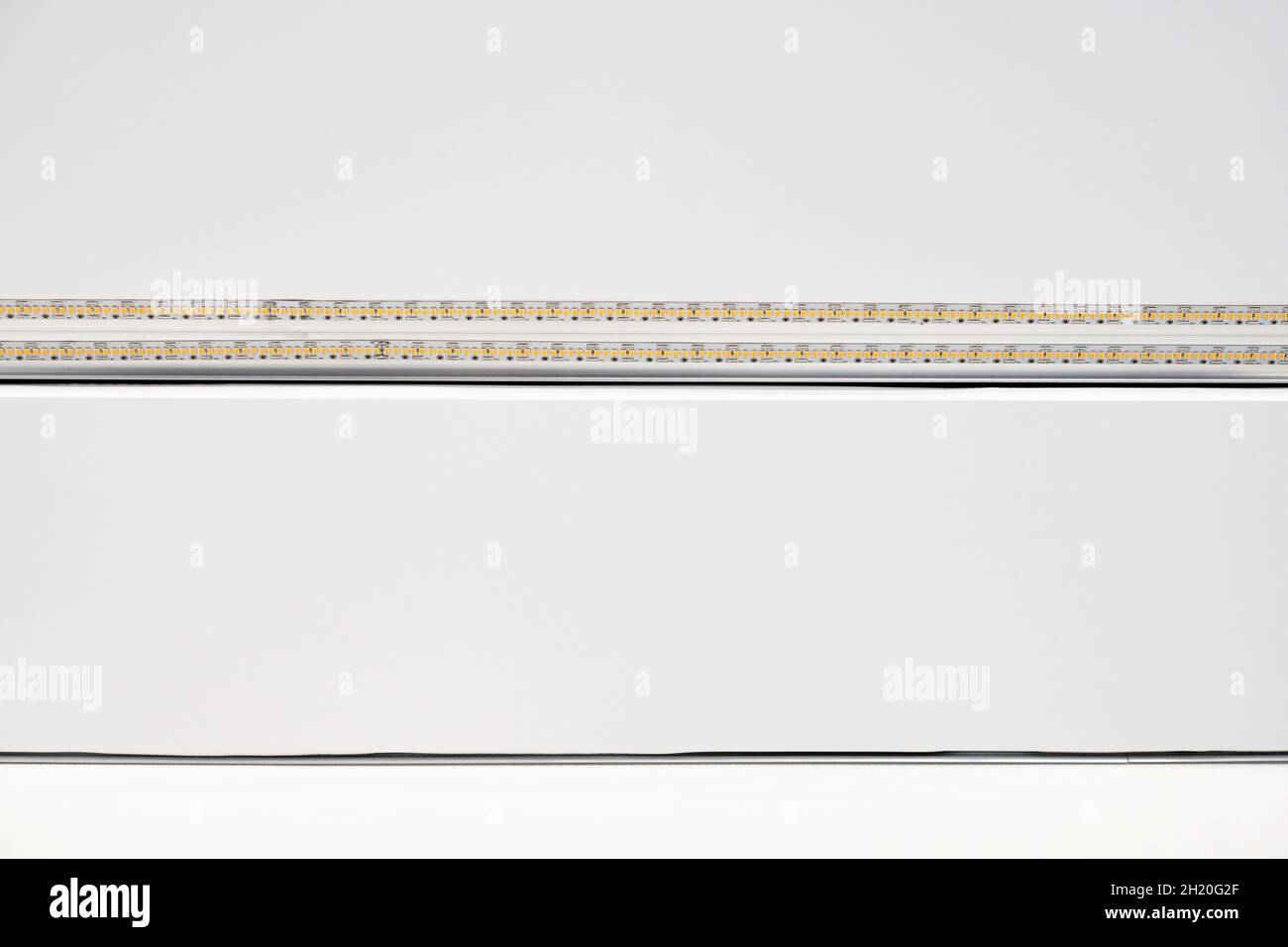 Lampada a LED a striscia con profilo in alluminio su soffitto bianco stretch in casa o in appartamento, da interno in primo piano. Concetto di ristrutturazione della casa. Costruzione moderna, e. Foto Stock