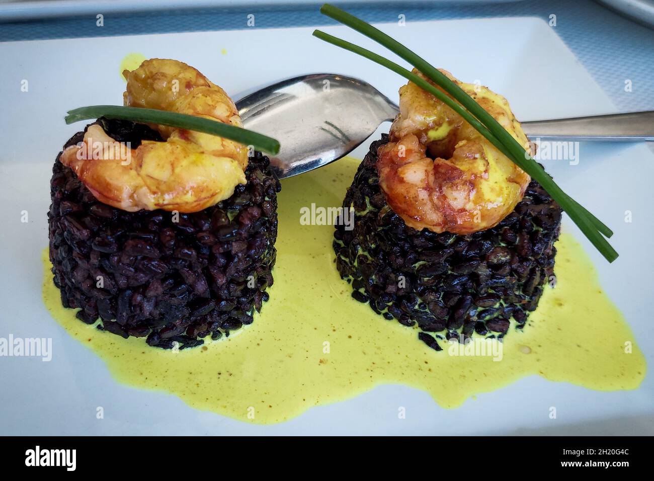 Riso nero con salsa di gamberi e curry e erba cipollina. Foto Stock