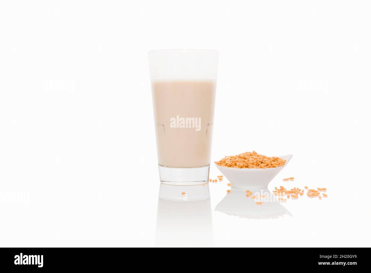 Un bicchiere di latte di grano su una superficie bianca Foto Stock