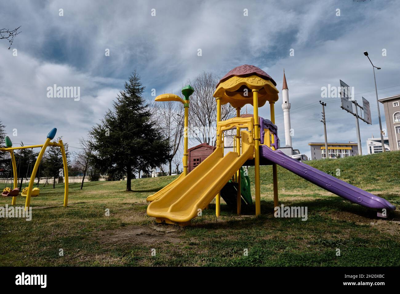 Parco giochi colorato su erba verde e percorso a piedi insieme con enormi e magnifiche nuvole cumulo Foto Stock