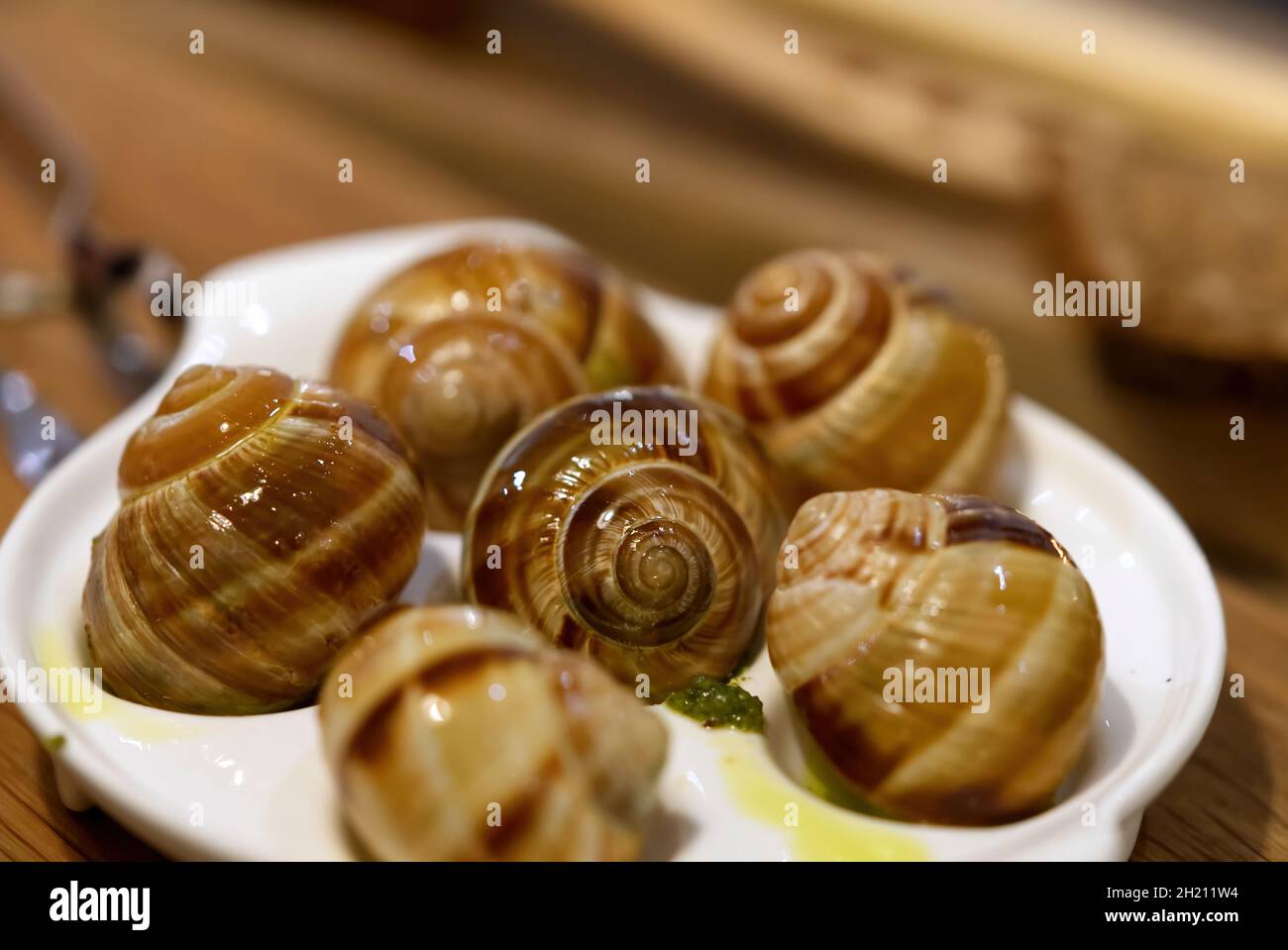 Helix Aspersa Muller piatto di lumaca in un ristorante. Lumache commestibili con burro e condimenti. Foto Stock