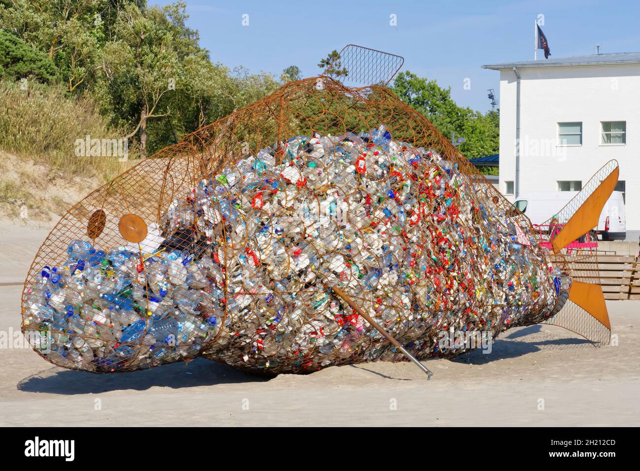 dumpster sotto forma di un pesce enorme con immondizia all'interno. Foto Stock