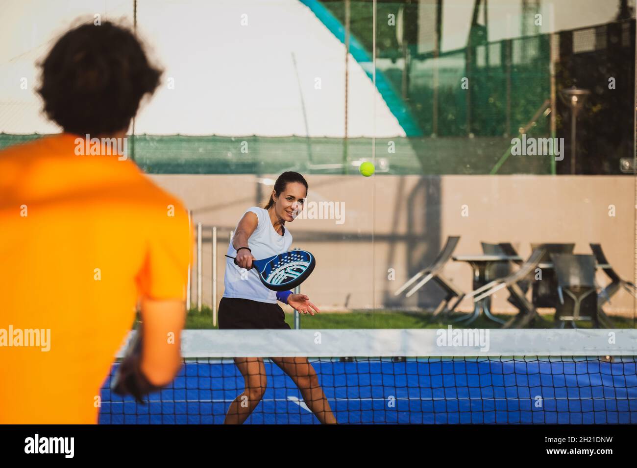 Il giovane insegnante sta monitorando la lezione di padel di insegnamento al suo studente - Coach insegna alla ragazza come giocare a padel sul campo da tennis all'aperto Foto Stock