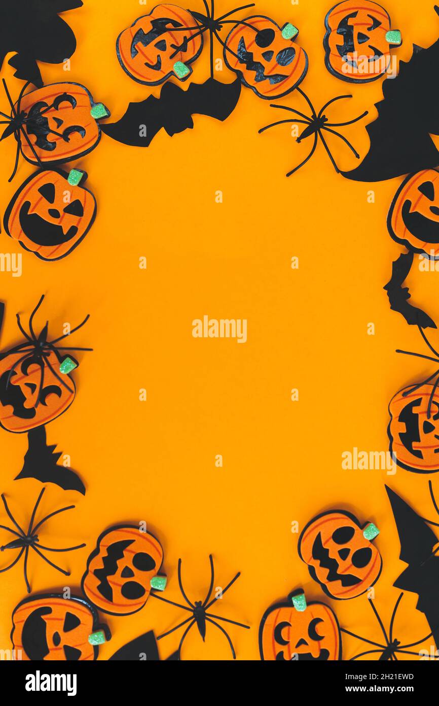 Buon Halloween. Zucche jack o lanterna, ragni, pipistrelli telaio su sfondo arancione piatto con spazio per il testo. Decorazioni di Halloween su carta gialla Foto Stock