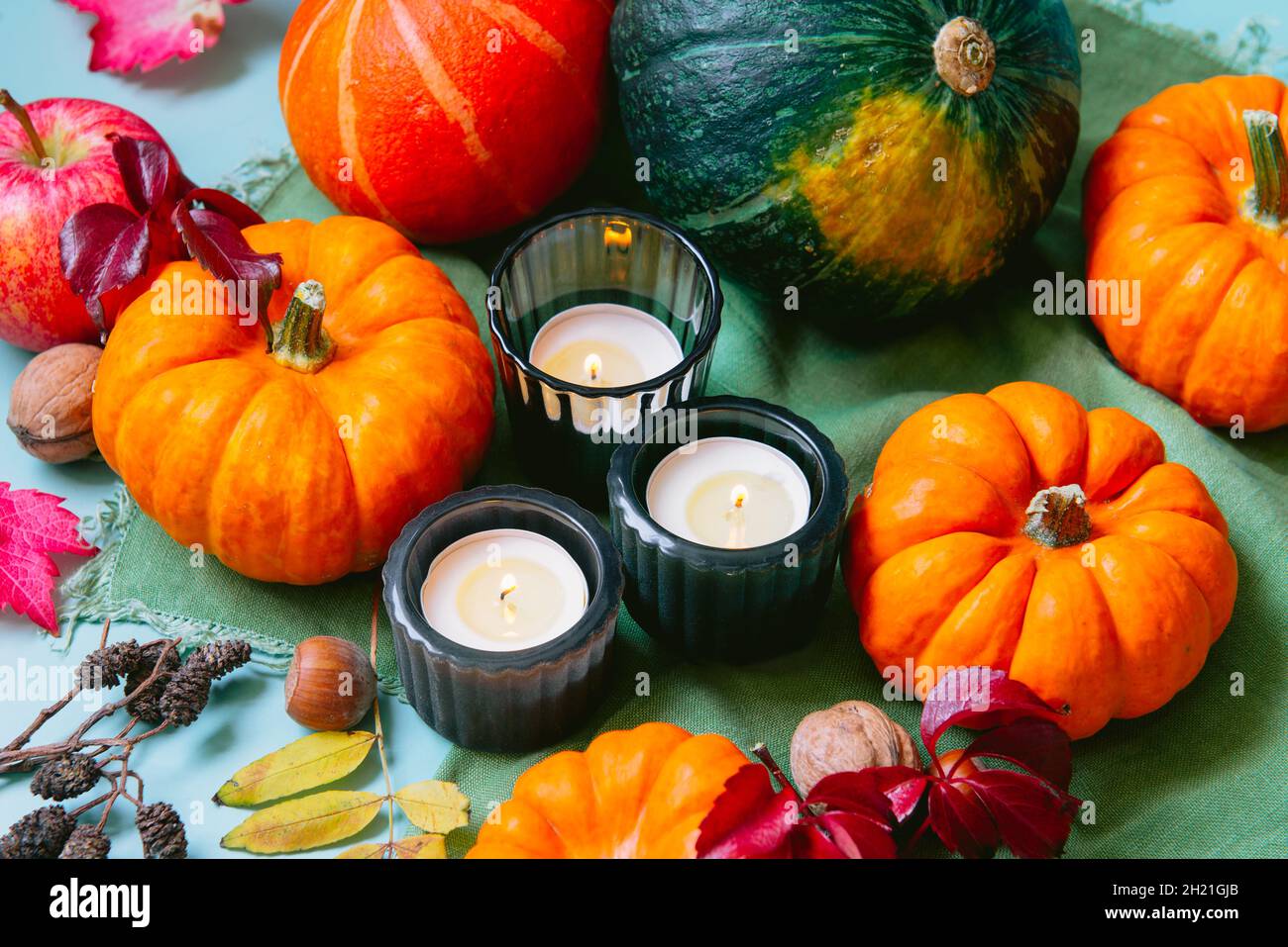 Thanksgiving autunno raccolta composizione con zucche decorative, mele, noci, foglie cadute e candele brucianti su sfondo toni terra. Conc. Autunnale Foto Stock