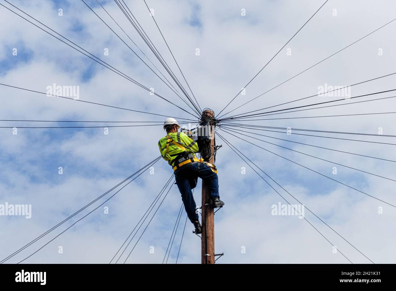 Kelly Group Telecommunications, ingegnere delle telecomunicazioni al lavoro in cima a un palo telegrafo, Londra, Inghilterra Regno Unito Foto Stock