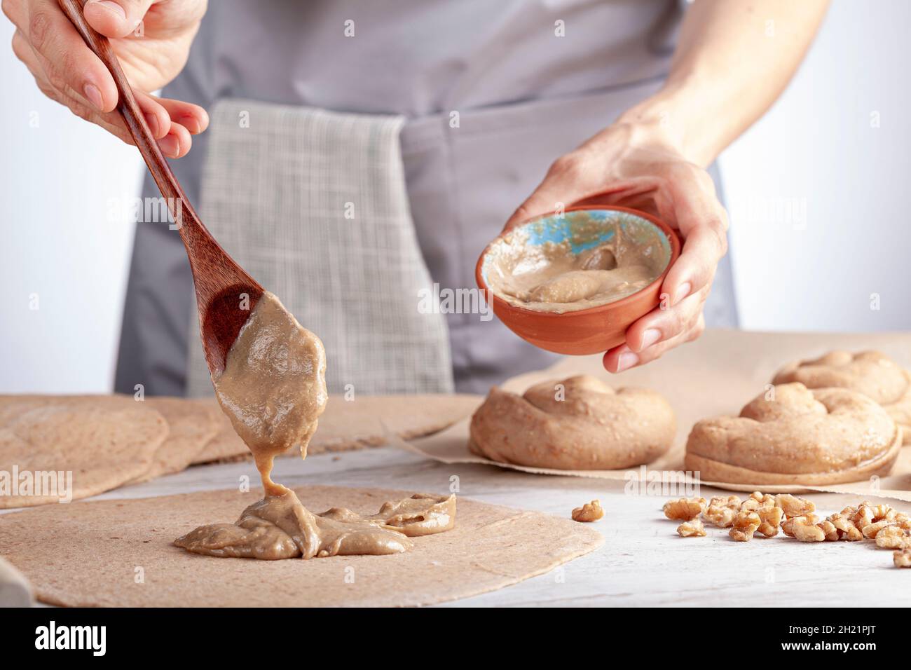 Primo piano immagine isolata di una donna caucasica che prepara dolci rotoli di pasticceria turca con tahini e petimezi (tahin pekmez) si mescola gli ingredienti e. Foto Stock