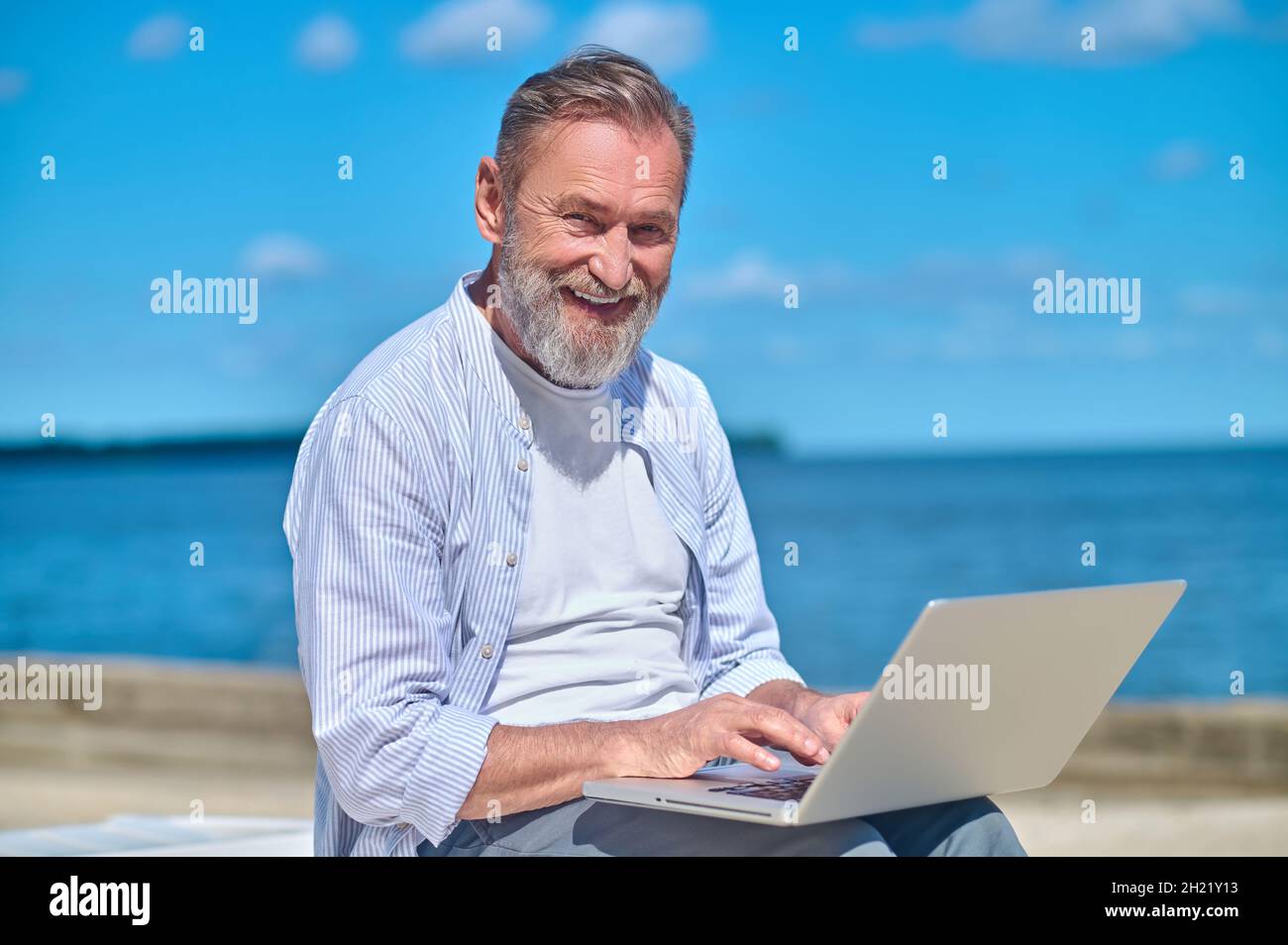 Uomo maturo sorridente con notebook in natura Foto Stock