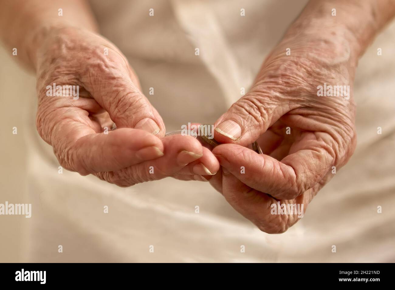 Le mani stropicciate della vecchia donna contando piccole monete Foto Stock