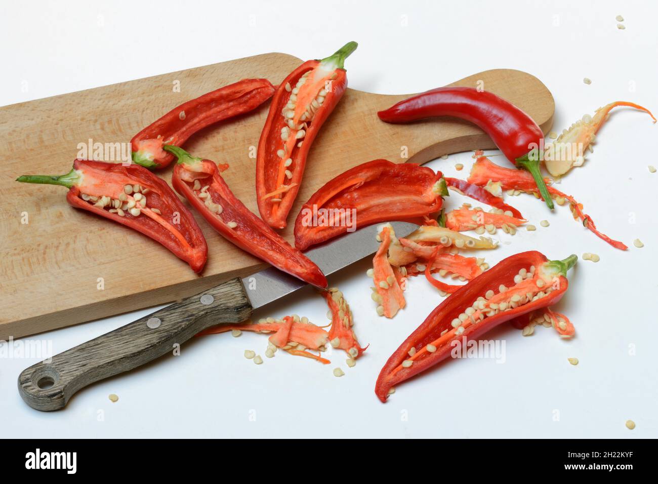 Peperoni rossi tagliati su tavola di legno con coltello, Germania Foto Stock