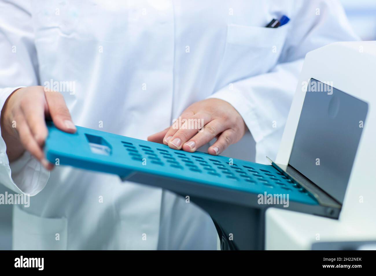 Giovane assistente di laboratorio con campione che lavora in un laboratorio con attrezzatura di laboratorio, Friburgo, Baden-Wuerttemberg, Germania Foto Stock