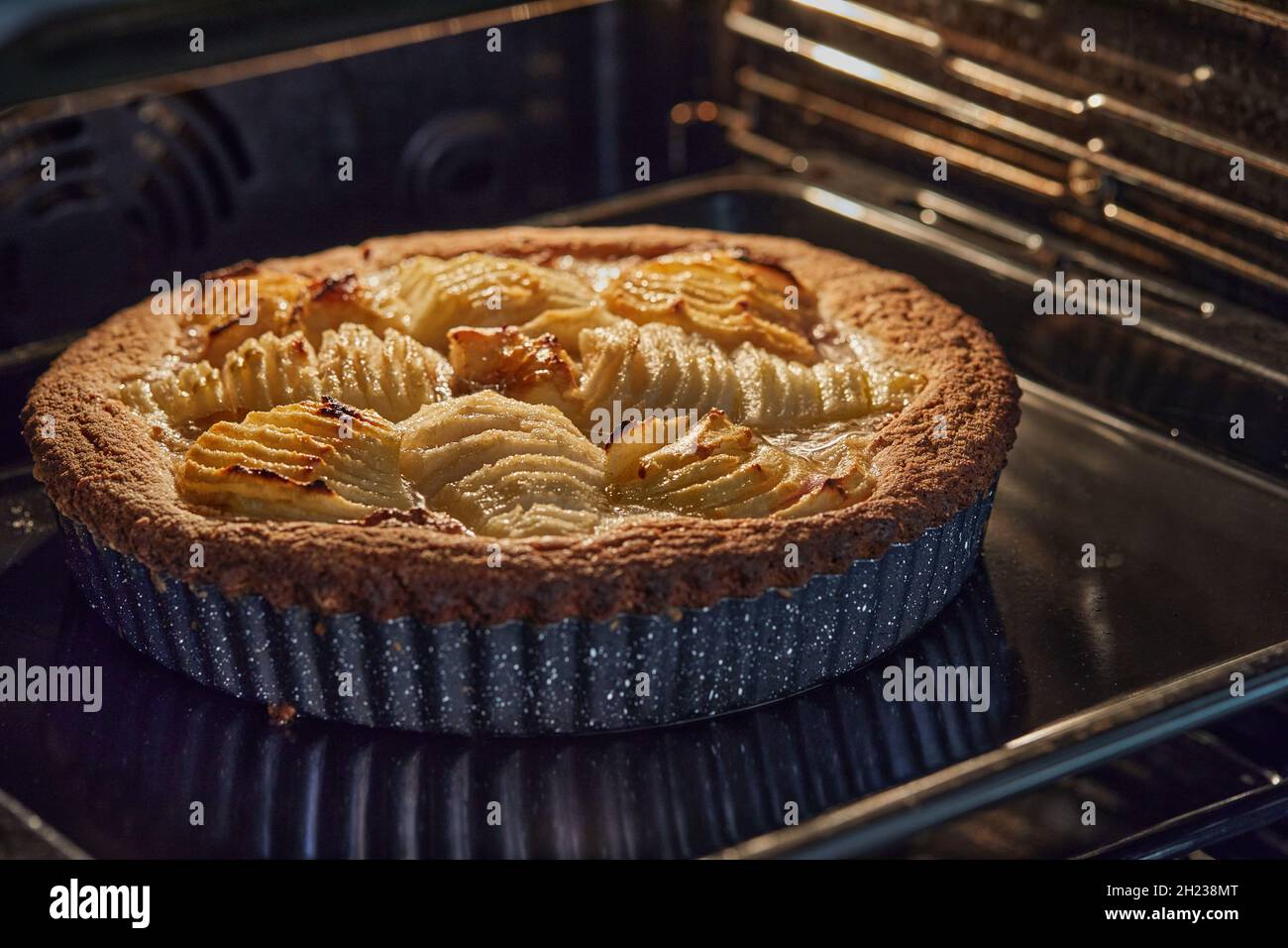 Torta al forno con pere e pesche in metallo in un forno elettrico Foto Stock