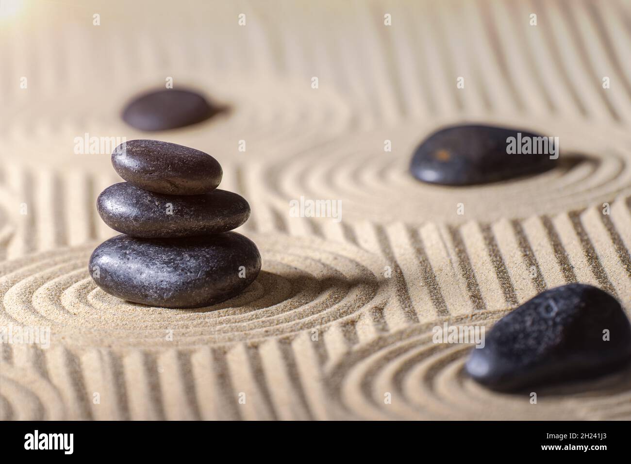 Pietre nere impilate sul giardino Zen con sabbia. Spiritualità, relax e armonia concetto. Foto Stock