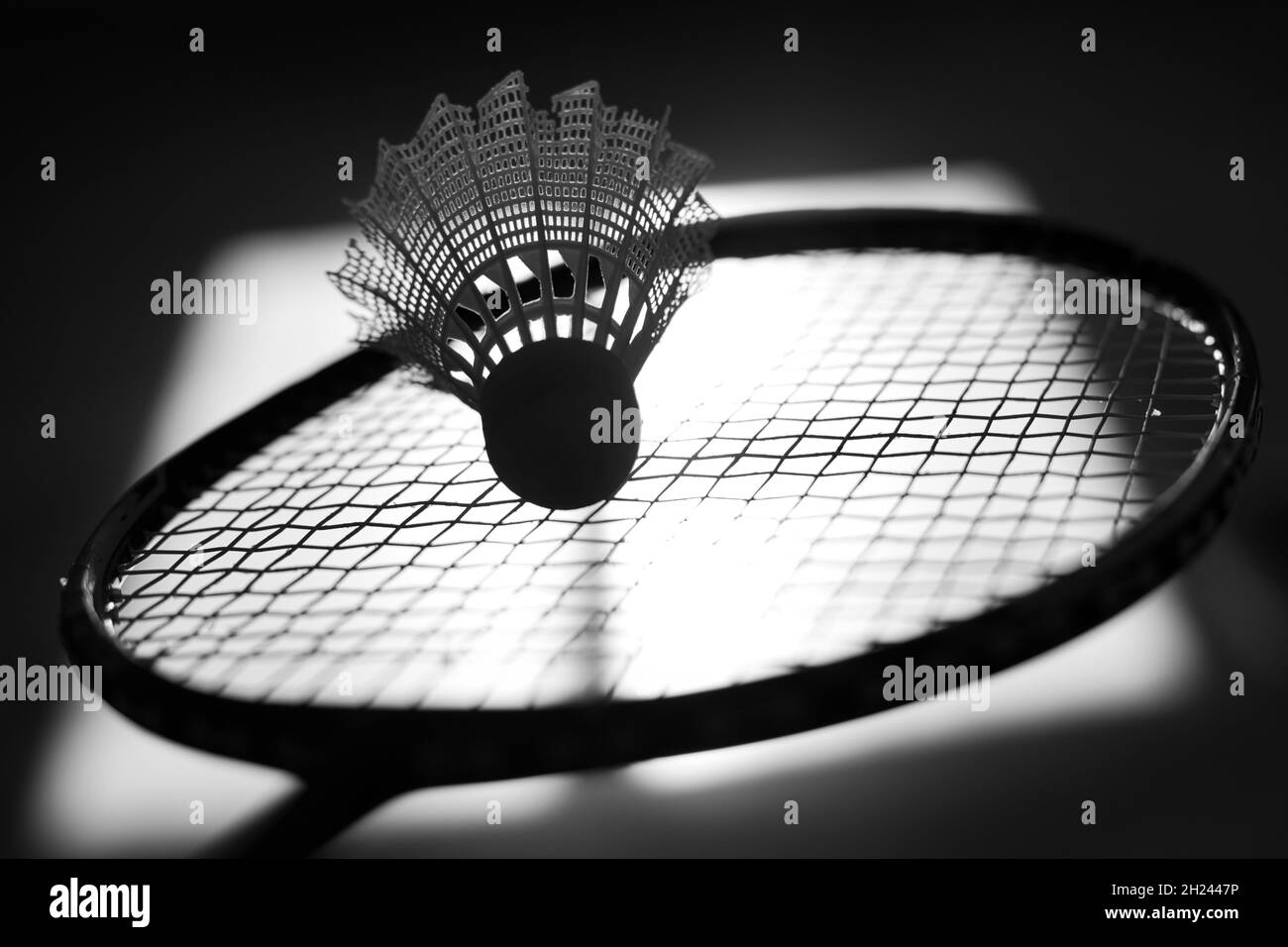 Silhouette di racket e shuttleock badminton sullo sfondo dell'ombra dalla finestra. Gioco attivo e mobile. Sfondo monocromatico astratto. Foto Stock