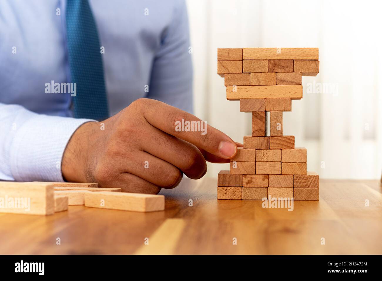 Uomo costruzione blocchi di legno forma di vetro di ore. Concetto di gestione aziendale e temporale. Foto Stock