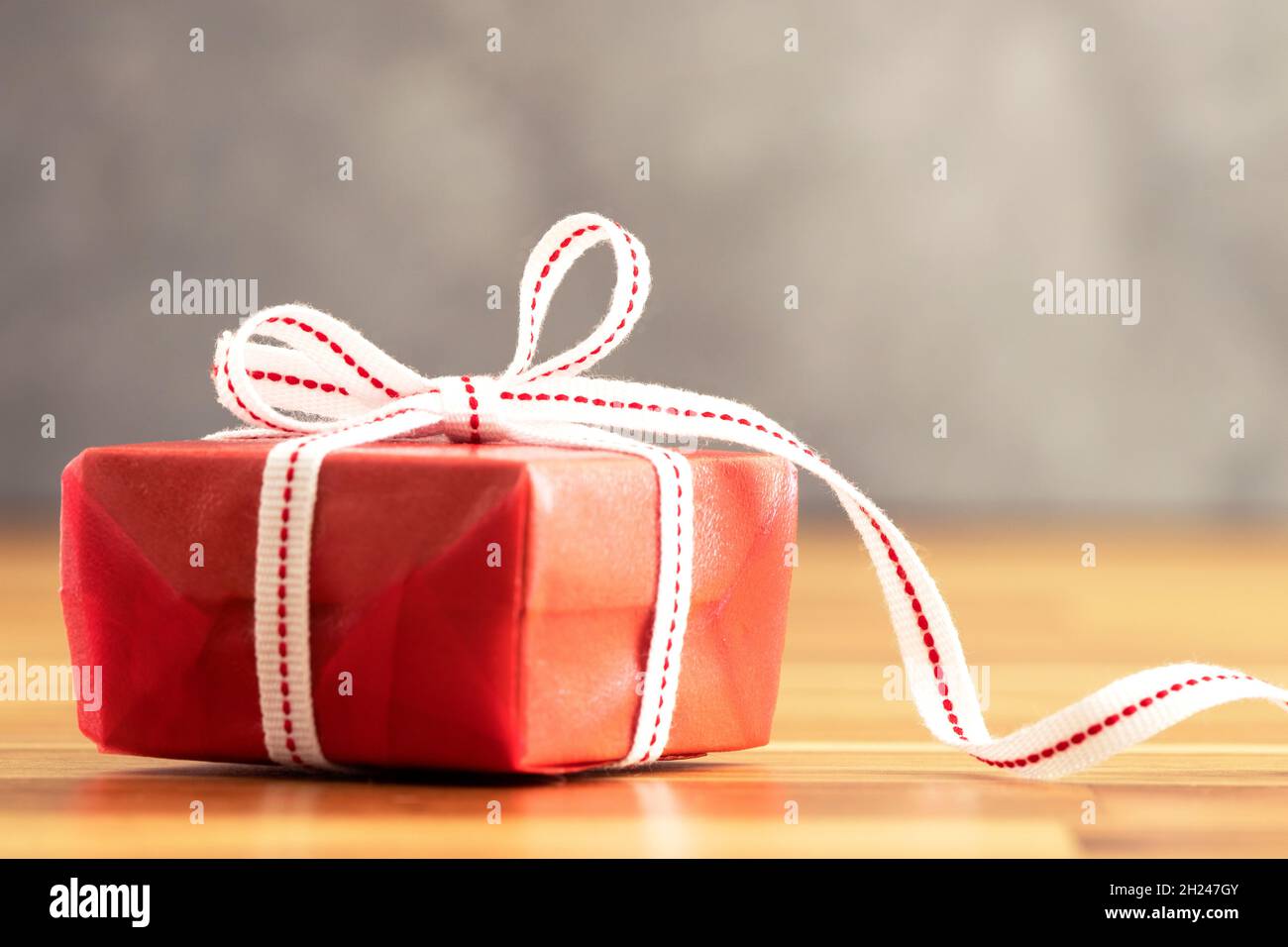 Primo piano della confezione regalo rossa con nastro bianco. Amore, dono e concetto del presente. Foto Stock