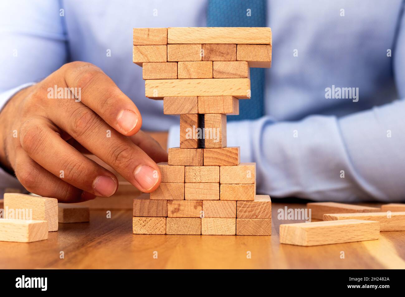 Uomo costruzione blocchi di legno forma di vetro di ore. Concetto di gestione aziendale e temporale. Foto Stock