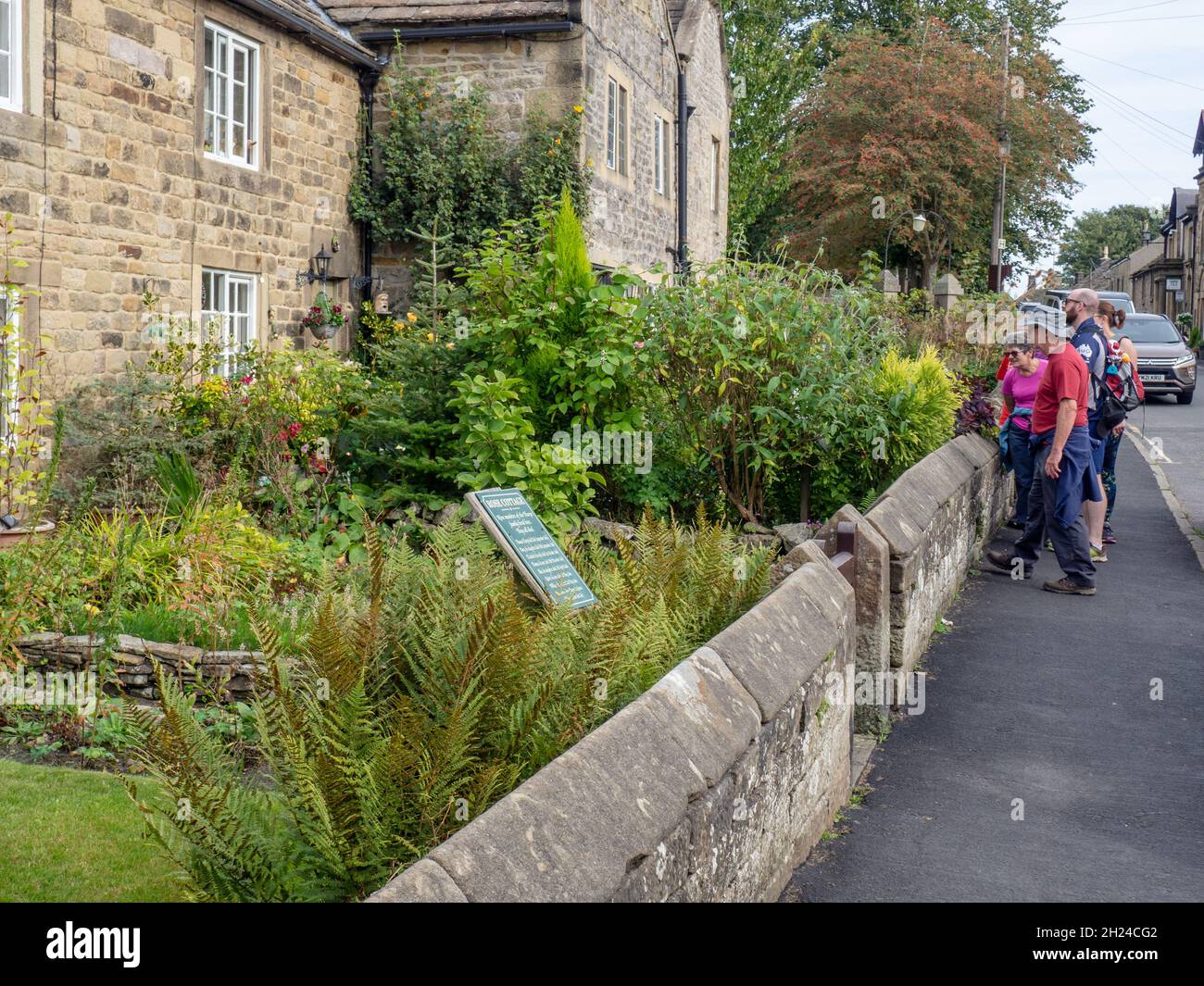 I visitatori del cosiddetto villaggio della peste di Eyam vedendo uno dei cottage della peste, Derbyshire, Inghilterra, Regno Unito Foto Stock