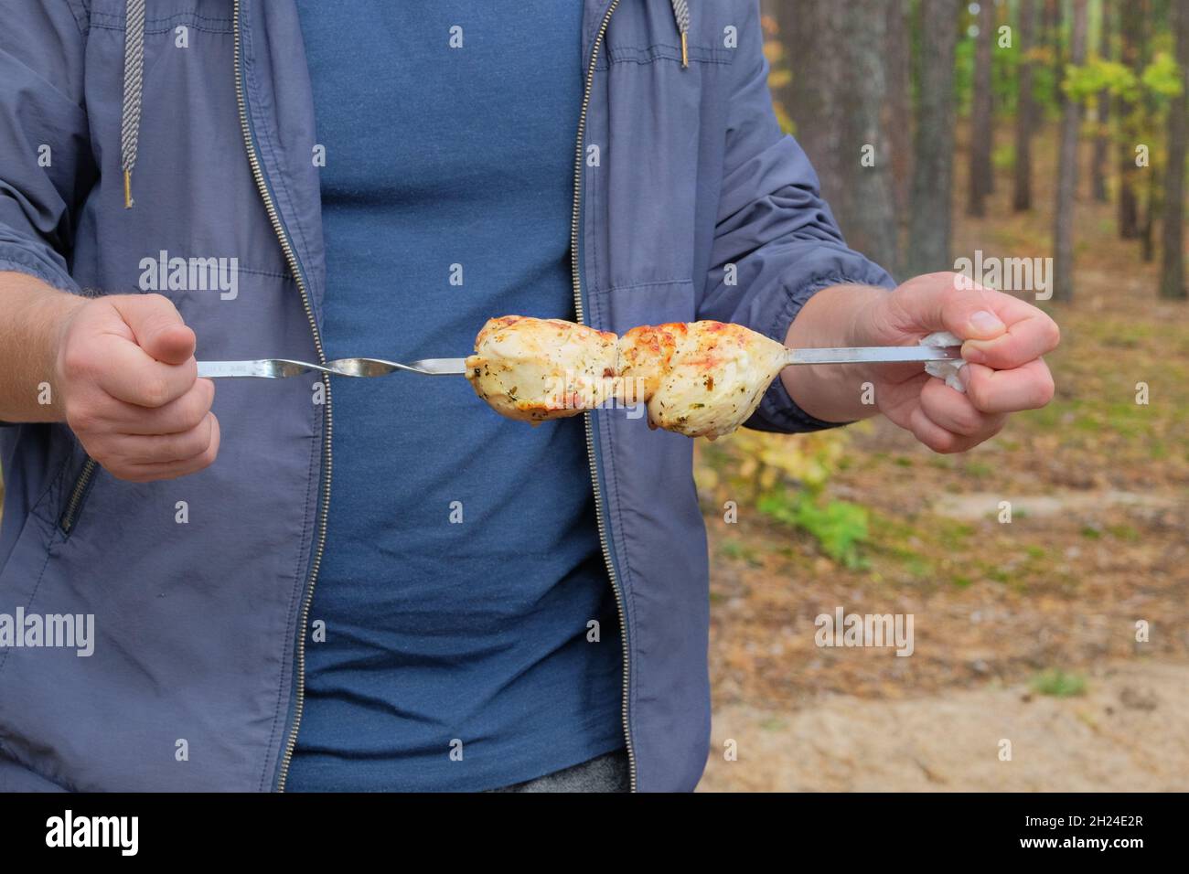 Carne alla griglia nelle mani di un uomo in natura. Friggere il kebab sulla griglia all'aperto. Foto Stock