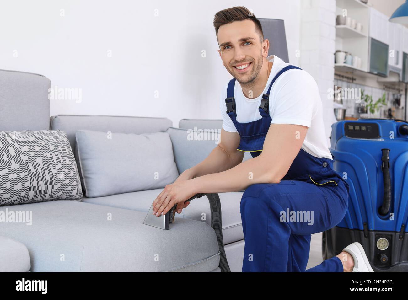 Lavoratore di sesso maschile che rimuove lo sporco dal divano con un  aspirapolvere professionale in ambienti interni Foto stock - Alamy