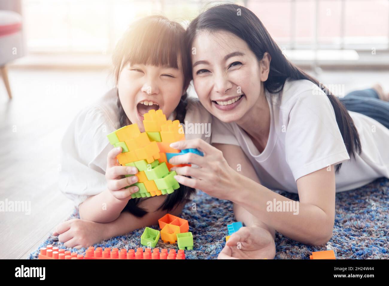 Godetevi felice amore asiatico famiglia madre e piccola ragazza carina sorridente giocare con giocattoli costruzione giocattolo o costruzione a casa Foto Stock