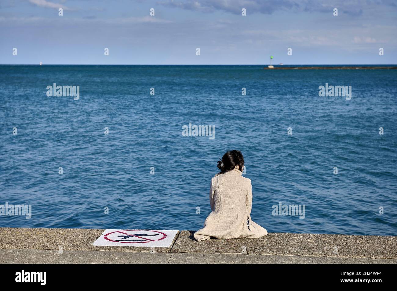 Stati Uniti, Illinois, Chicago: Giovane donna vista da dietro seduto sul molo, guardando lo skyline sul lago Michigan, lungo 494 km e 190 km w Foto Stock