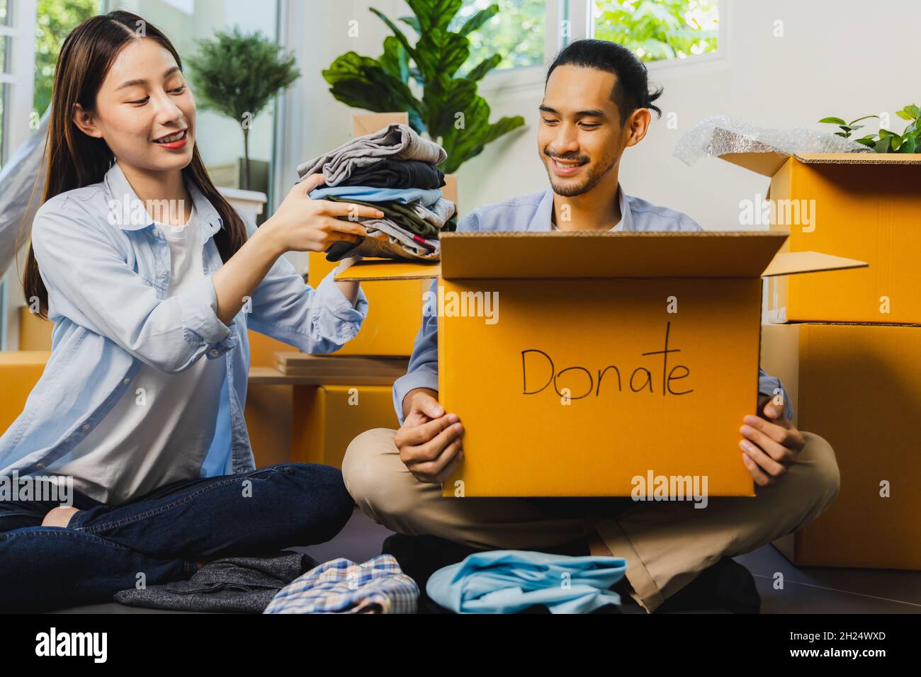 Primo piano scatola di donazione, uomo che tiene abiti imballaggio e donna piegare abiti e prepararsi a dare la gente povera Foto Stock