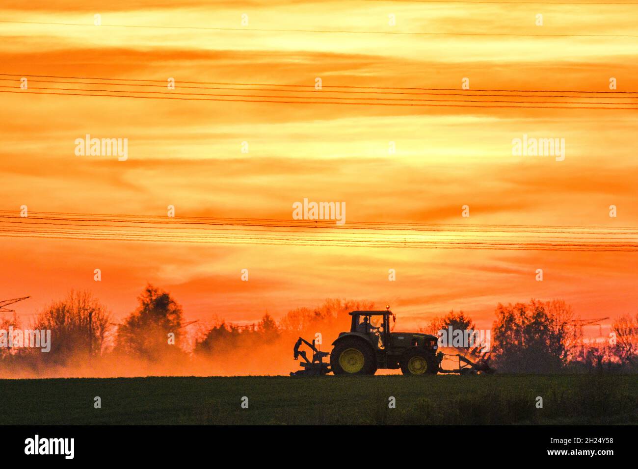 Lavoro agricolo al tramonto. Trattore in un campo Foto Stock