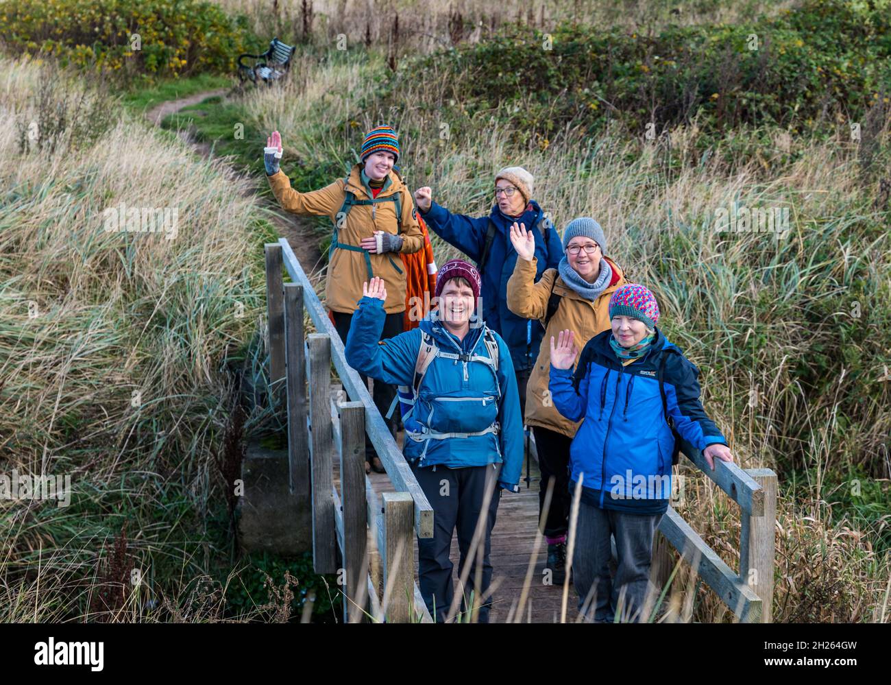 East Lothian, Scozia, Regno Unito, 20 ottobre 2021. Pellegrinaggio COP26: Gruppi di comunità di base sulla tratta scozzese di una passeggiata fino a COP26. I partecipanti ritengono che la COP26 non porterà i cambiamenti significativi necessari per combattere il cambiamento climatico. Nella foto: Parte del gruppo su una passerella di legno sul percorso costiero John Muir Way a Longniddry Bents Foto Stock