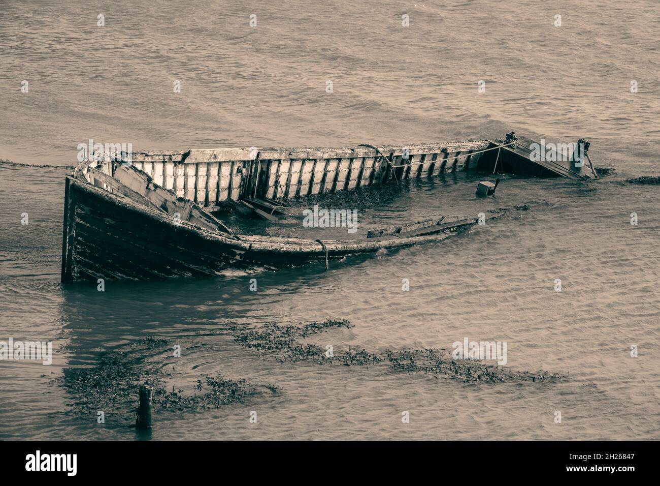 Abbandonato clinker costruito barca parzialmente sommerso su una riva del fiume Foto Stock