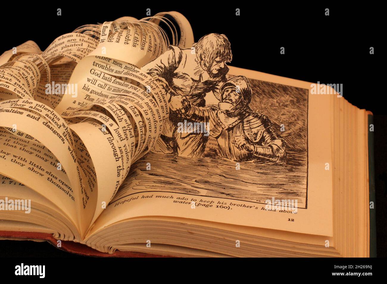 Scultura del libro fatta dal progresso del Pilgrim da John Bunyan speranzoso salvare suo fratello da annegamento arte della carta woth sfocato sfondo bokeh. Foto Stock