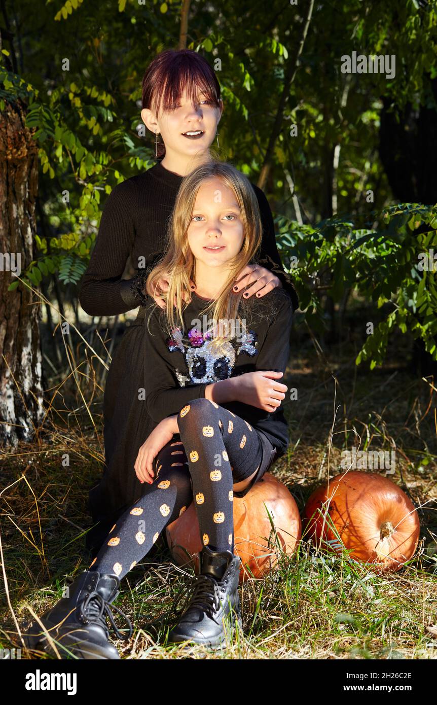 Due sorelle felici nella foresta di Halloween. Divertenti bambini in costumi di carnevale all'aperto a Halloween trick o delizia. Buon Halloween! Foto Stock