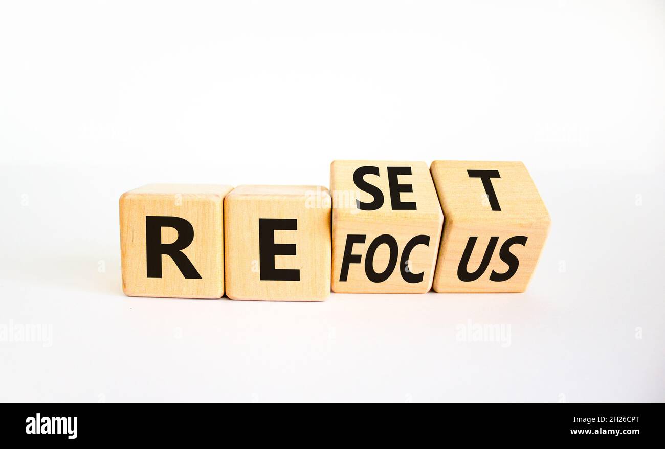 Rifocalizzazione e simbolo di reset. L'uomo d'affari girò i cubi e cambiò la parola 'focus' in 'set'. Bella tavola bianca, sfondo bianco. Business refocu Foto Stock