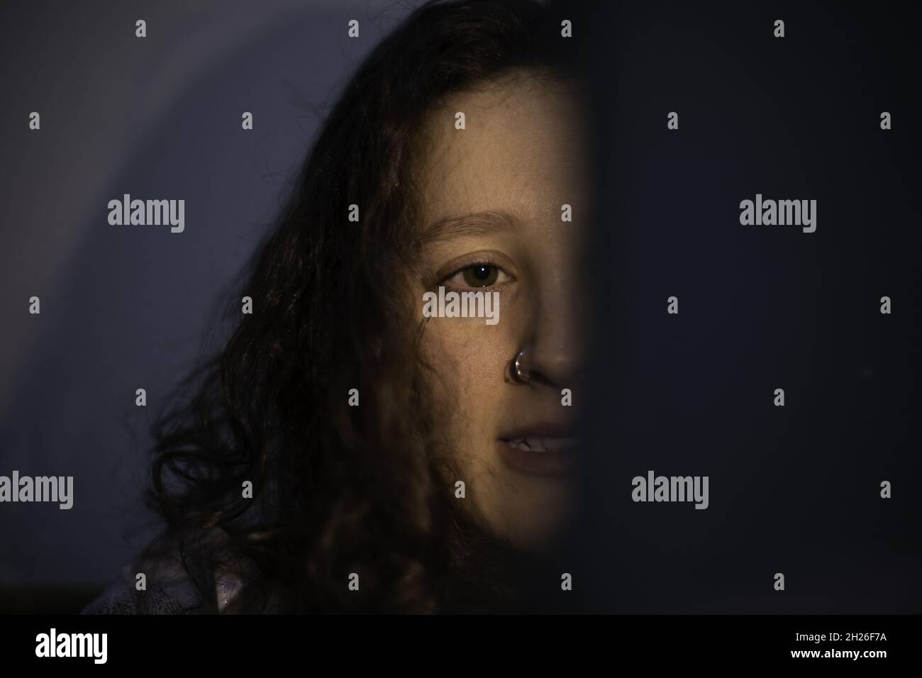 Primo piano del volto di una giovane donna nelle tenebre. Foto Stock